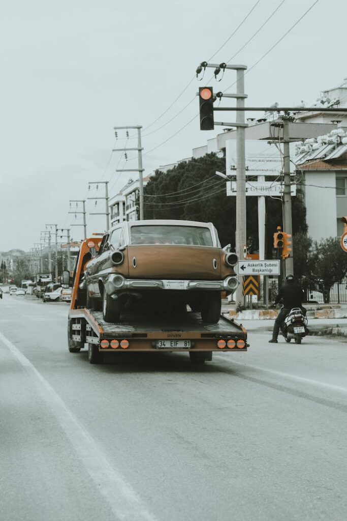 Truck Towing Vintage Car through Streets